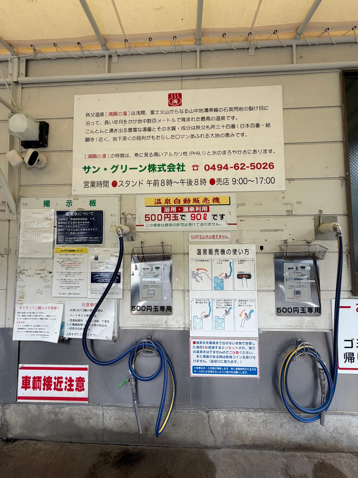 スタンドの看板のアップ。満願の湯の由来文、PH9.1の表示、温泉自動販売機 浴用・温泉利用 500円玉で90リットル、この源泉は飲用の許可は受けておりませんの表示